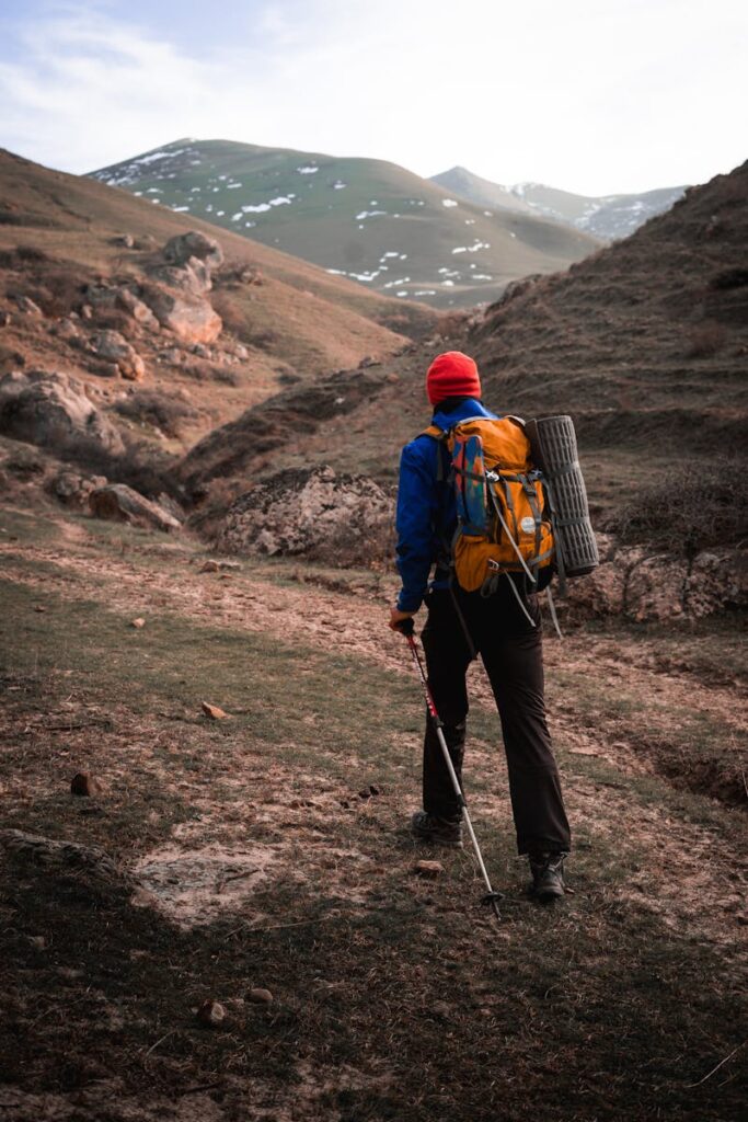 An adventurer walking alone through rugged mountain terrain.